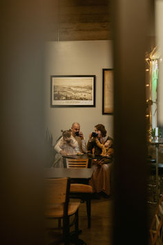 three people sitting at a table taking pictures