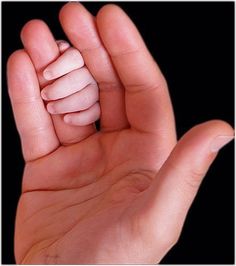 a person's hand holding a tiny white object