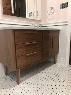 a bathroom with a sink, mirror and wooden cabinet in front of the tub area