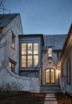 a house that is lit up at night with lights on the front door and steps leading to it