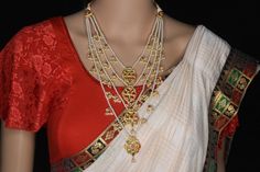 a woman wearing a red and white saree with gold jewelry on her neck,