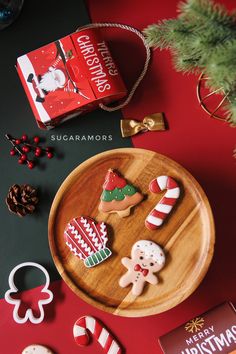 some christmas cookies are on a wooden plate next to other holiday decorations and candy canes