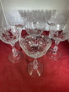 four wine glasses sitting on top of a red table