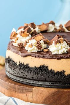 a cake with chocolate, cream and nuts on top is sitting on a wooden platter