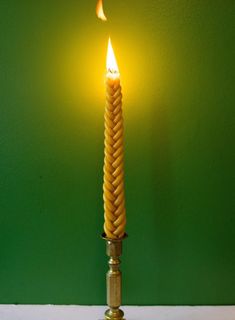 a candle that is sitting on a table with a green wall in the back ground