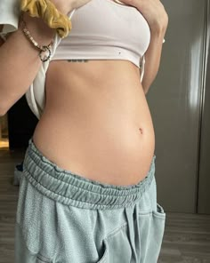 a pregnant woman taking a selfie with her cell phone in front of her face