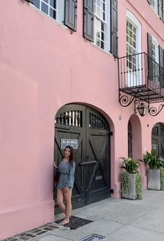 a woman standing in front of a pink building