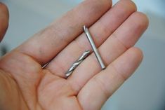 a person holding two small screws in their hand