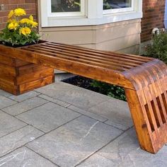 a wooden bench sitting on top of a stone walkway next to a house with flowers in it