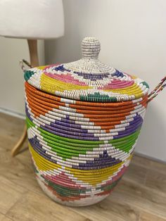 a multicolored basket sitting on top of a hard wood floor next to a lamp