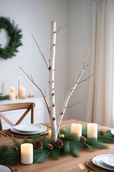 the table is set with candles and pine branches