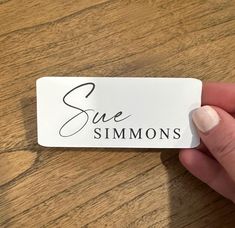 someone holding up a white business card with the word sue simmons on it in cursive writing