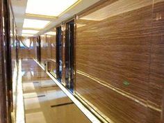 an empty hallway with glass doors and wood panels on the walls, leading to another room