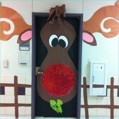 a door decorated to look like a reindeer with a red nose and green leaf on it