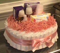 a cake decorated with baby items and pink ribbon on a countertop in front of a mirror