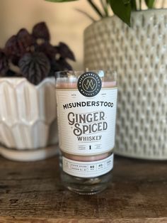 a bottle of ginger spice sitting on top of a wooden table next to a potted plant