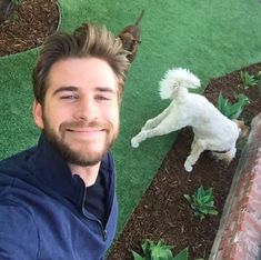 a man is taking a selfie with his dog in front of him on the grass