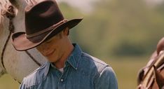 a man wearing a cowboy hat standing next to a horse