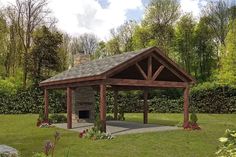 a gazebo in the middle of a grassy area with flowers and trees around it