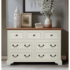 a white dresser with drawers and flowers on top