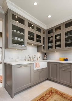 a large kitchen with gray cabinets and white counter tops, an area rug on the floor