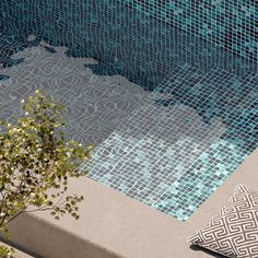 a pillow sitting next to a swimming pool with blue tiles on the floor and walls