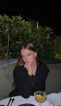 a woman sitting at a table with food and drinks