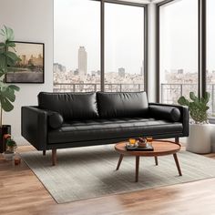 a living room with a black leather couch and coffee table in front of large windows