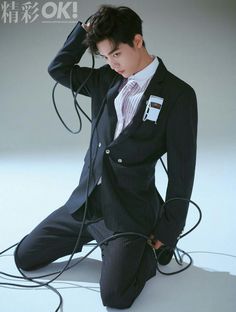 a man in a suit and tie sitting on the ground with wires attached to his head