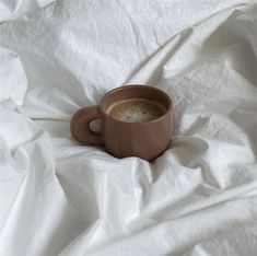 a cup of coffee sitting on top of a white sheet