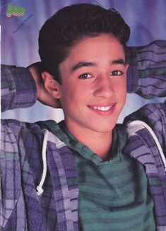 a young boy is smiling and posing for the camera with his hands on his head