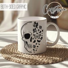 a white coffee mug with a skull and butterflies on it sitting on a woven place mat