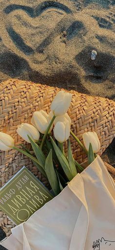 some white flowers and a book on the sand