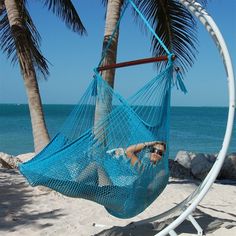 a woman sitting in a hammock on the beach