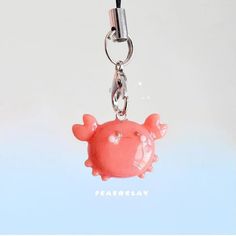 a pink pig keychain hanging from a metal hook on a blue background with the word freakfo clay written below it