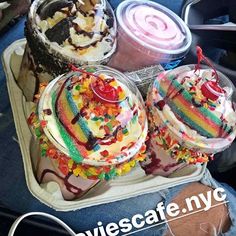 three ice cream sundaes are in a plastic container with candy and sprinkles