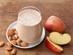 an apple and almond smoothie on a plate next to some nuts