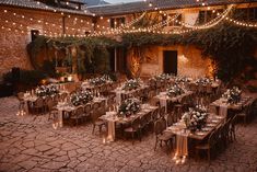 an outdoor dining area with tables, chairs and string lights strung over the building's courtyard