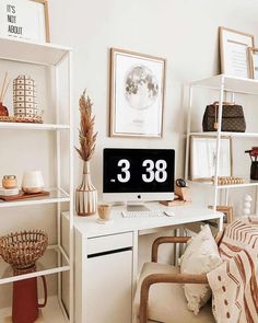 a white desk topped with a computer monitor next to a shelf filled with books and other items