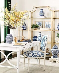 a white table topped with blue and white vases next to a white desk covered in flowers