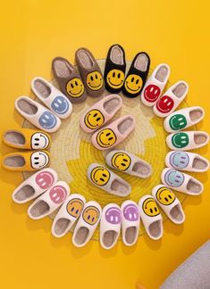 several pairs of slippers with smiley faces are arranged in a circle on a yellow background