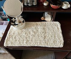 a white rug on top of a wooden table next to a potted plant and other items