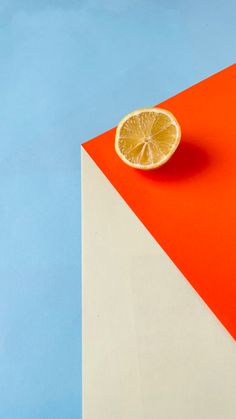 an orange slice sitting on top of a white and red triangle shaped object with blue sky in the background