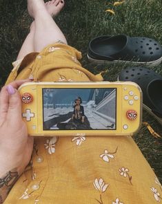 a person laying in the grass with a video game on their phone