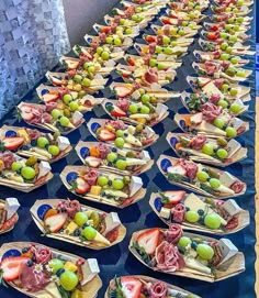 a long table filled with lots of different types of food on trays next to each other