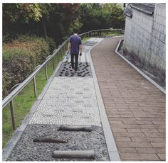 a man walking down a walkway made out of rocks