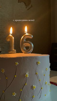 a birthday cake with two lit candles on it and the number six is decorated in white frosting