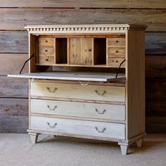 an old wooden dresser with two drawers in front of a wood paneled wall behind it