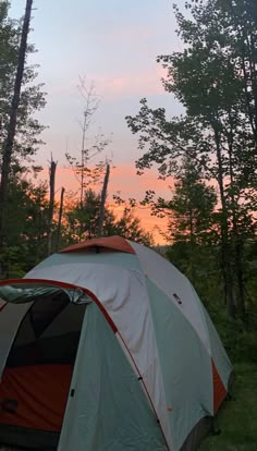 a tent pitched up in the woods at sunset