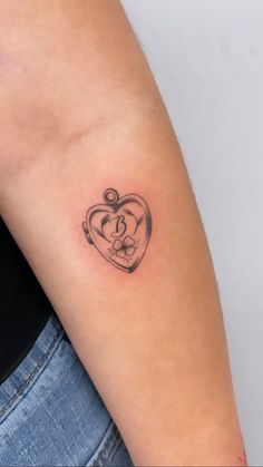 a woman's arm with a small heart tattoo on the left side of her arm